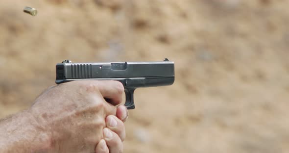 Close up footage of a hand gun firing in a firing range with cartridge flying away