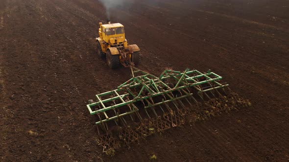 Aerial View of a Powerful Yellow Tractor with Great Effort on the Hook Performing Plowing Tillage