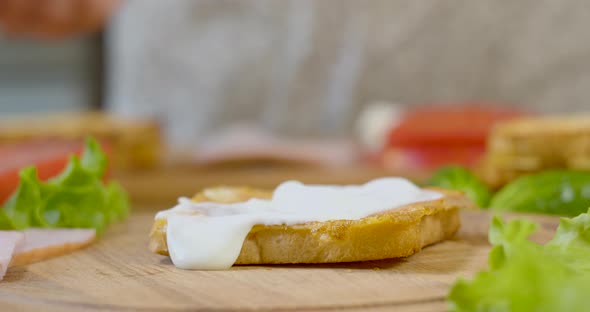 Female Chef in the Kitchen of the House Collects a Sandwich