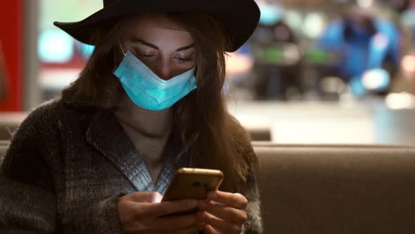 Close Up Woman in Coat and Hat Using Smartphone on City Street Against Window with Lights