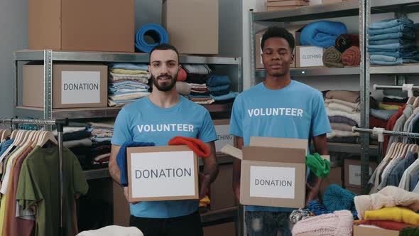 Portrait View of the Diverse Male Volunteers Holding Cupboard Boxes with Clothes and Looking at the