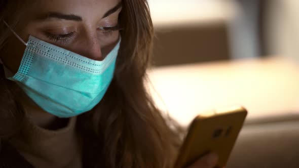 Close Up Woman in Protective Medical Mask Standing Using Smartphone on City Street with Bokeh Lights