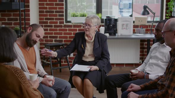 Psychotherapist Talking to Group of People in Circle at Aa Therapy Meeting