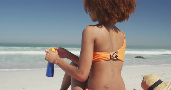 African American woman applying sunscreen at beach