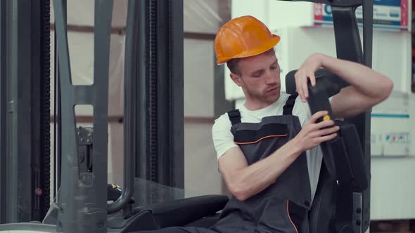 Young Worker in Uniform i Sitting in a Forklift Car