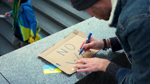 Protester preparing placard against war in Ukraine at a rally, Prague.