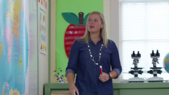 Teacher gives lesson in school classroom and students raise hands