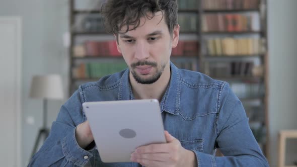 Casual Young Man Browsing Internet on Tablet