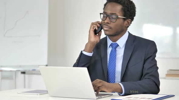 African Businessman Talking on Phone at Work