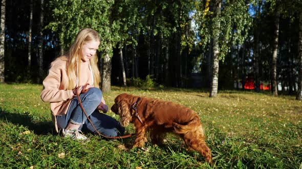 Fair Haired Girl Smiles and Plays with Russian Spaniel Dog