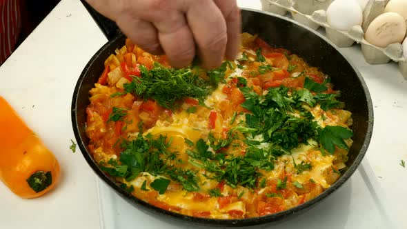 Chef Sprinkles with Herbs Fried Eggs Shakshuka in Vegetables Sauce Who Preparing on Frying Pan