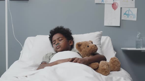 Boy Sleeping with Toy Bear in Hospital