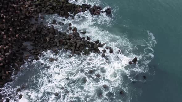 Aerial view of sea wave crashing tetra concrete block or wave breaker stone