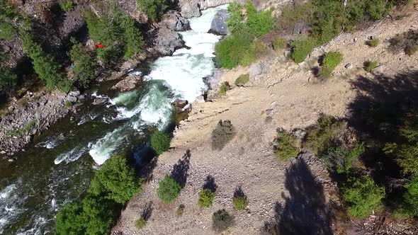 Kayaks being carried along a trail to avoid a dangerous waterfall in a steep and rugged canyon