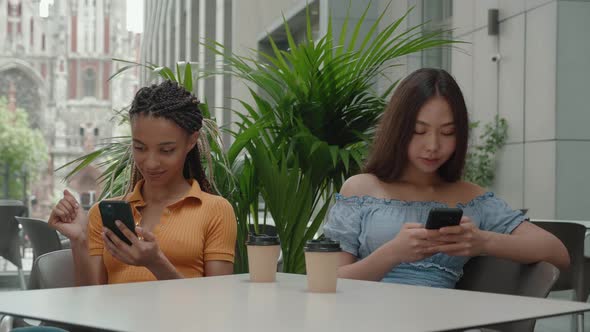 Asian and Mixed Ra e Young Girls Holding Smartphone Use Social Media Drink Coffee in Coffee Shop