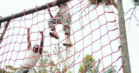 Military soldier climbing rope during obstacle course