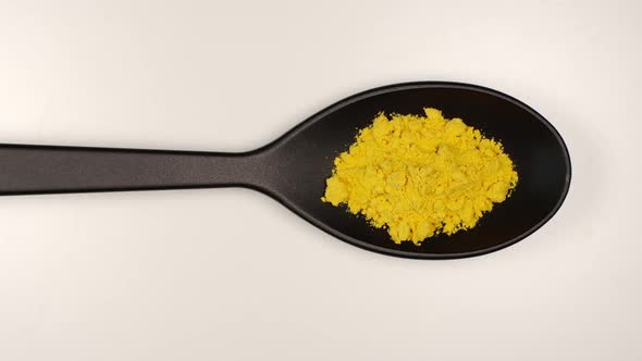 Turmeric powder fill a plastic spoon on a table