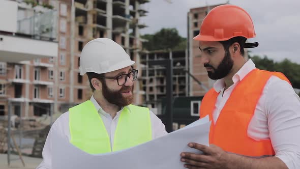 Architect Expert Engineers Talking and Analyze Design Plan Standing Under Construction Site