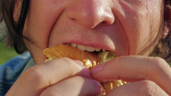 A Man is Biting a Cheeseburger with Great Appetite