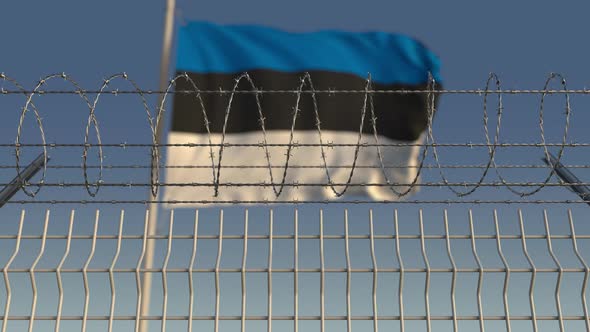 Waving Flag of Estonia Behind Barbed Wire Fence