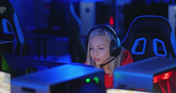 Young Woman Sits in Headphones at a Modern Computer Club Plays an Online Game