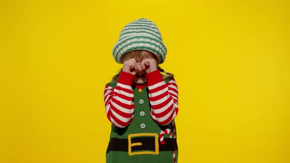 Kid Girl in Christmas Elf Santa Helper Costume Crying and Wipes Tears