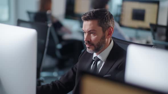 Serious Adult Bearded Man Working on Decktop Computer While Working in Big Open Space Office