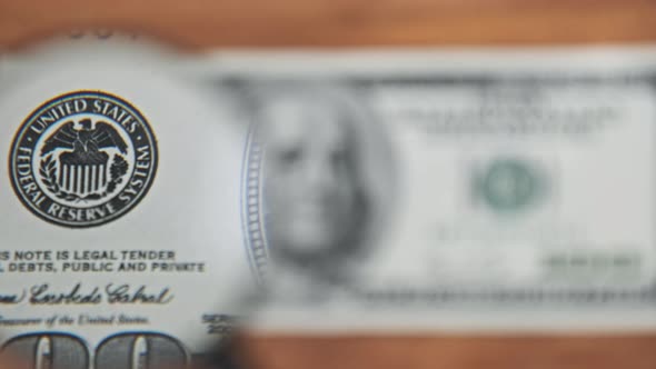 One Hundred Dollars Look Under Magnifying Glass on Wooden Table