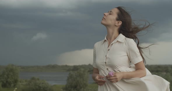 Headshot Portrait of Girl Breathing Fresh Windy Air on Rainy Stormy Sky Background. Serious Woman