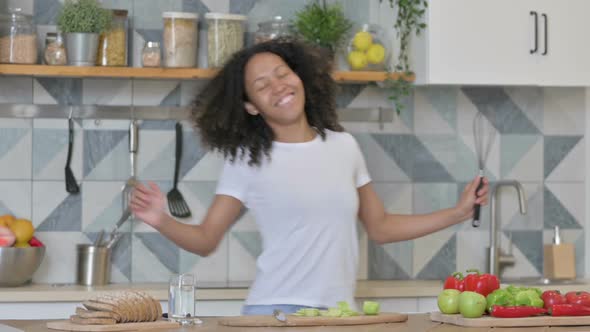 Young African Woman Dancing While Cooking in Kitchen