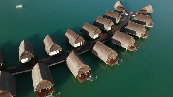 Adult woman walks on wooden pathway past overwater bungalows in Fiji, aerial