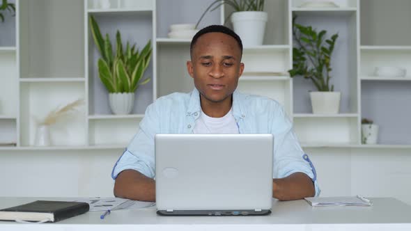 Young African-American Is Sitting at Home Office, Smiling at the Camera. Portrait of Satisfied Young
