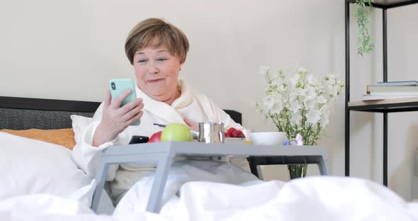 Old Cheerful Woman Smiling, Waving and Blowing Kiss While Having Video Call with Family. Good