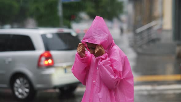 Young Smiling Woman with a Pink Raincoat While Enjoying a Walk Through the City on a Rainy Day