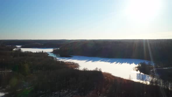 AERIAL: Sun Rays Shining on Beautiful Winter Day While Flying Over Forest