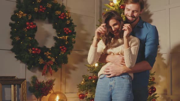 Smiling beautiful woman and her handsome boyfriend posing in New Year interior 