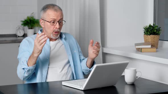 A Happy Elderly Man Enjoys the Good News While Looking at His Laptop