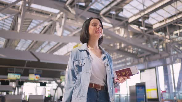 Asian young attractive woman passenger walking in airport terminal to boarding gate to airplane.