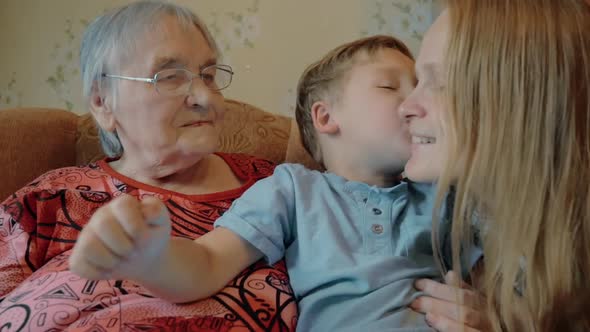 Little boy expressing love to mother and grandmother with kisses