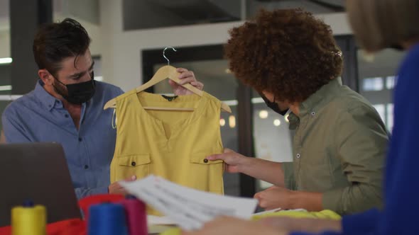 Mixed race clothes designers having video call wearing face masks