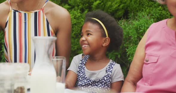 Happy african american grandmother with granddaughter having breakfast with family in garden