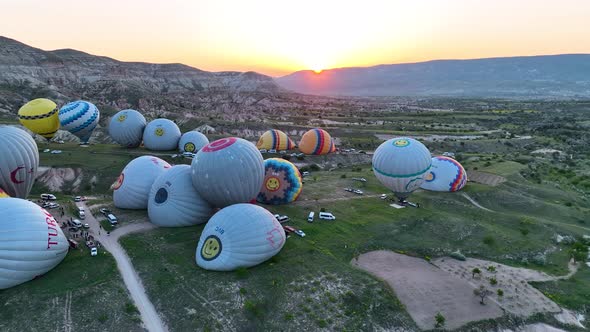 Hot air balloons fly over the mountainous landscape of Cappadocia, Turkey.