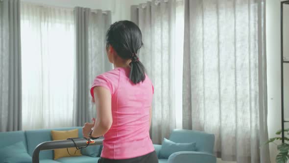 Back View Of Asian Woman Running On A Treadmill At Home