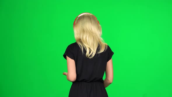 Back View of Woman Walks in Big Red Headphones and with a Smartphone and Dancing. Chroma Key