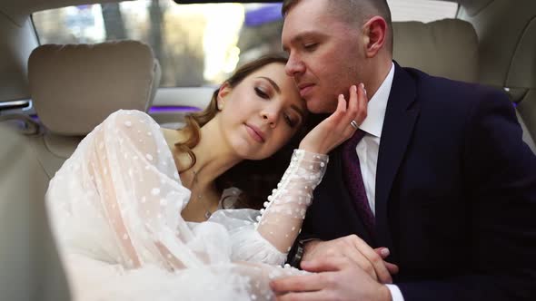 The Bride and Groom Hug Gently While Sitting in the Car