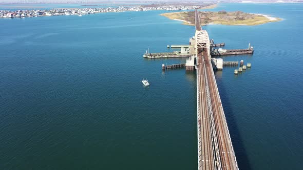 A high angle shot over elevated train tracks crossing a bay in Queens, NY. The camera dolly in over