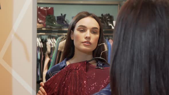 Attractive Woman Smiling To the Camera While Trying on a New Dress at the Store