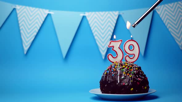 chocolate birthday cake with a burning candle number thirty nine, 39 on a blue background. Copy spac