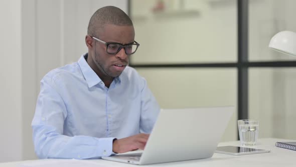 African Man Coughing While Working on Laptop