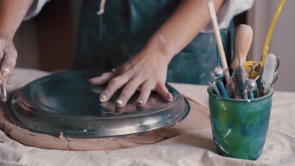 Potter Forming Clay Into a Dish By Using a Form and Tools To Get the Perfect Shape